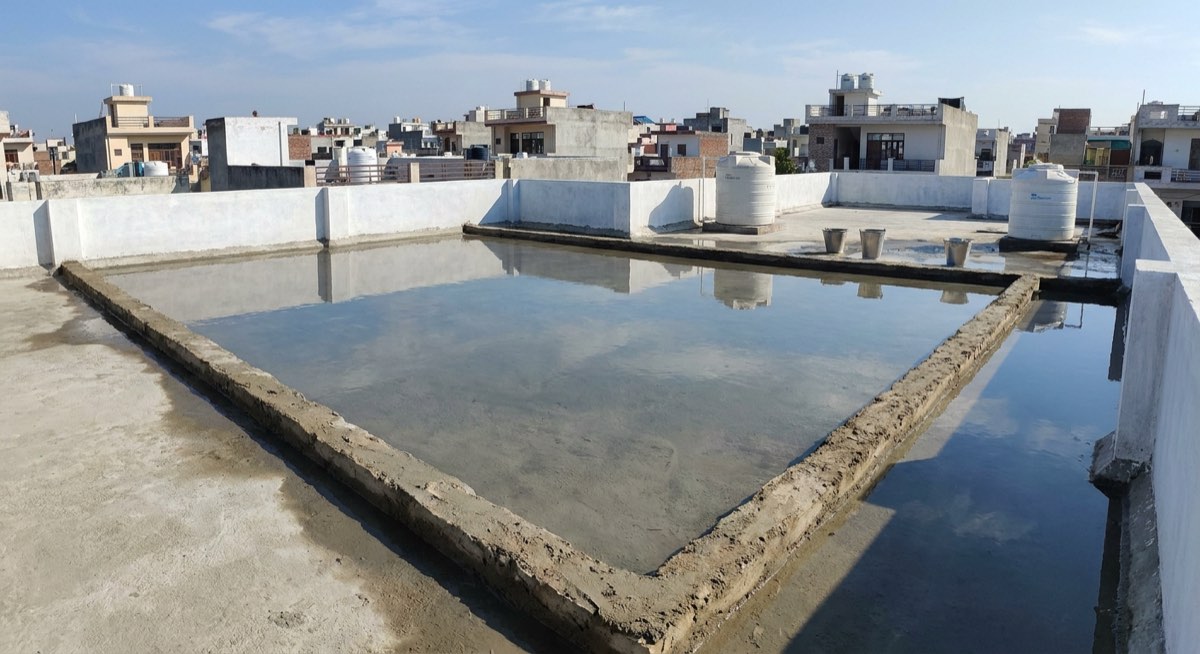 Completed terrace roof under flood test with ponded water held by temporary bunds